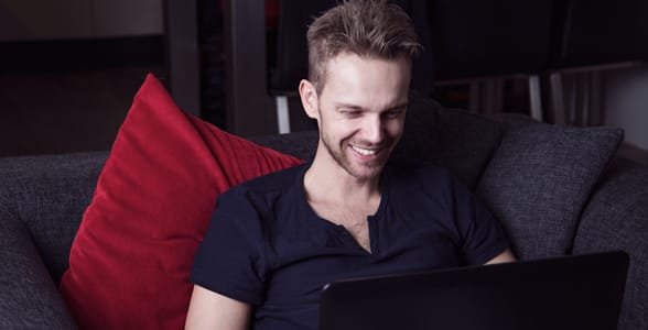 Photo d'un gars souriant à un ordinateur portable