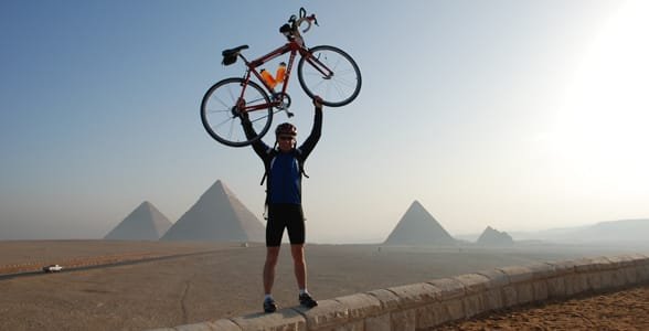 Foto von einem Mann, der mit seinem Fahrrad über seinem Kopf posiert