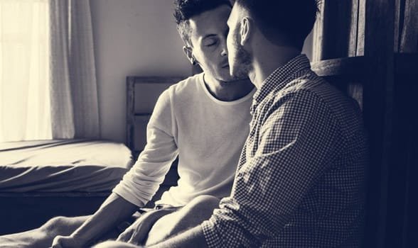 Foto van twee mannen die zoenen in bed