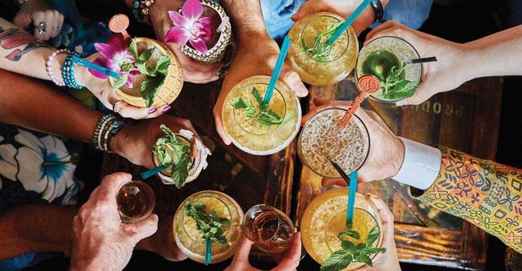 Foto van een groep mensen die drankjes omhoog houden bij Smuggler's Cove