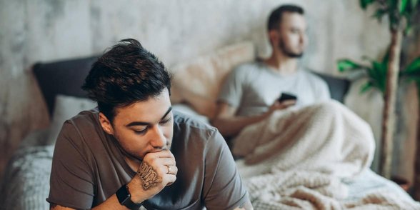 Photo de couple gay triste sur un lit