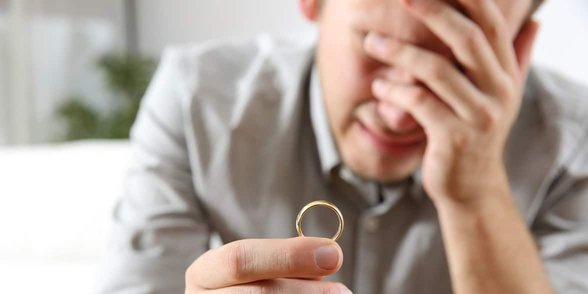 Foto van een huilende man met een trouwring