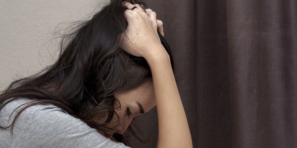 Foto einer Frau, die sich den Kopf hält