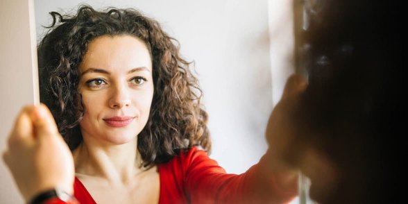 Foto van een vrouw die in de spiegel kijkt