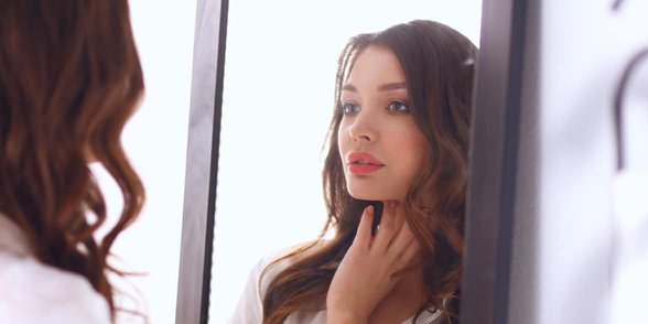 Foto di una donna che si guarda allo specchio